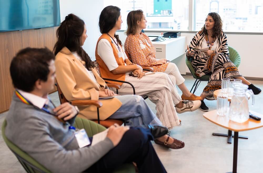 Painel de speakers no Café B na Copastur (#pracegover: da esquerda para a direita, um homem e quatro mulheres sentados em poltronas e cadeiras, debatendo sobre o tema do evento)