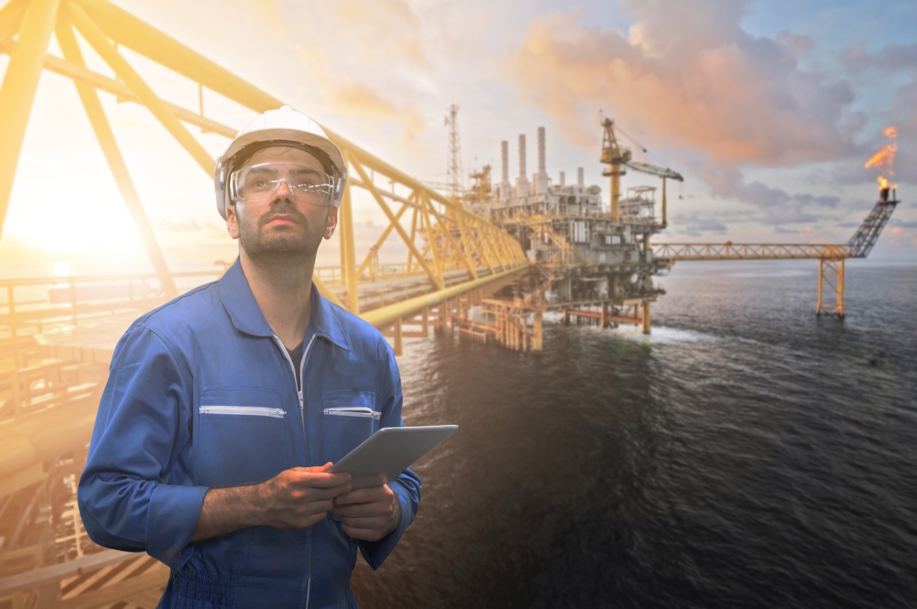 Ingeniero con una tableta frente a una plataforma offshore