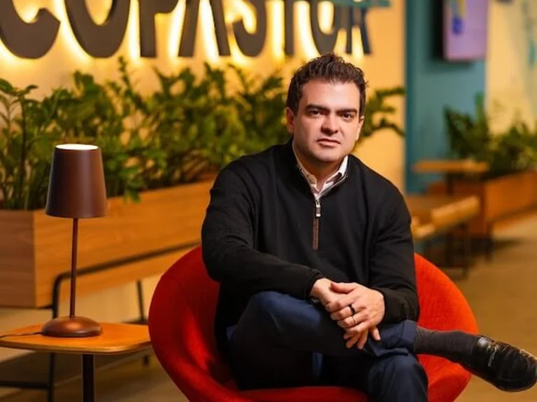 Edmar Mendoza, CEO da Copastur, sentado em uma poltrona vermelha em frente ao logotipo da Copastur