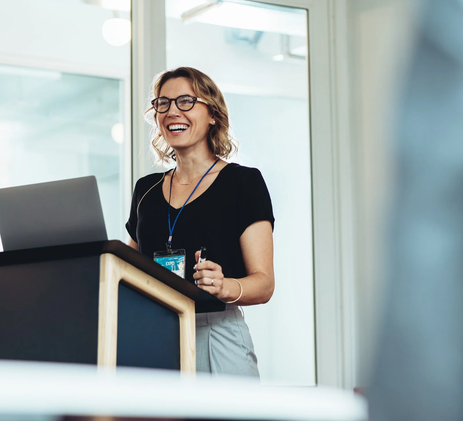 Mujer sonriente hablando desde un podio en un evento corporativo